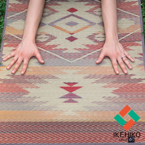 藺草編織瑜珈墊，以大地色系為底，搭配紅色、橘色、紫色和藍色的幾何菱形圖案，材質為藺草，質感樸實。