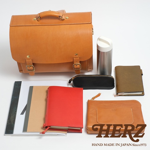 職人手作皮革橫式書包，搭配多款皮革小物，包含筆記本、化妝包、長夾及保溫瓶，整體呈現自然質樸的風格。