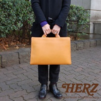 日本HERZ職人手作皮革簡約商務公事包，以溫暖的橘黃色皮革製成，配搭黑色大衣和皮靴，展現簡約質感。