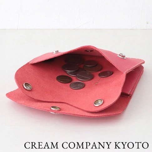 打開的粉紅色皮革零錢包，內有散落的硬幣，包包有兩個金屬按扣。