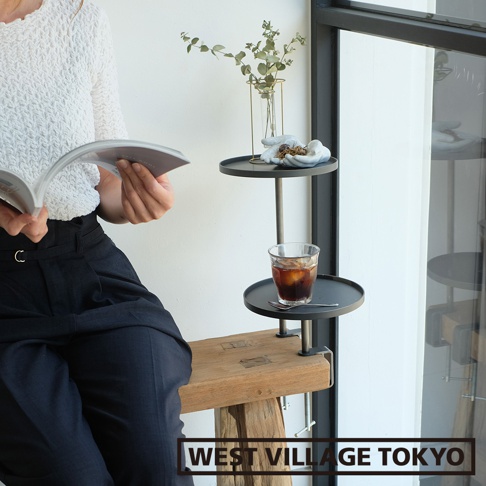 一組兩入的鐵製可夾式小物高低桌，黑色圓形桌面，搭配銀色金屬支架，可夾在木凳上，用於放置書本、飲料及裝飾品。