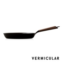 日本製黑色琺瑯鑄鐵平底鍋，配有木質手柄，鍋身呈現光滑質感，鍋緣略微傾斜，整體設計簡潔。