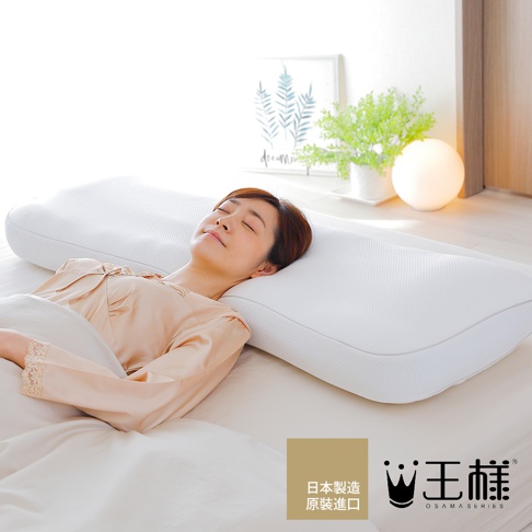 一位女性仰臥在白色寬長枕頭上，枕頭表面有細密的格紋織紋，枕頭呈現流線型設計，能完整支撐頭部與頸部，營造舒適的睡眠氛圍。