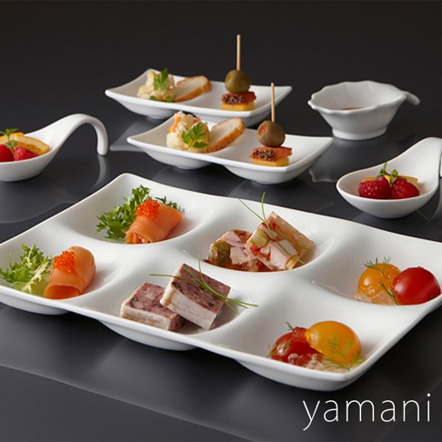 白色陶瓷六格小菜盤，擺放著煙燻鮭魚捲、肉醬、小番茄、橄欖串等精緻小點心，展現法式開胃菜的豐富色彩與層次。