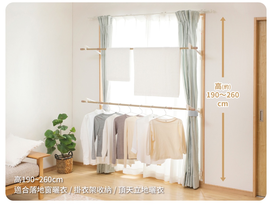 木紋頂天立地窗框曬衣架，兩層曬衣桿，上方掛著兩條白色毛巾，下方掛著多件淺色衣物，整體為木紋與淺色調，適合各種居家空間。