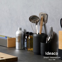 砂岩材質的一高一低兩個廚具收納筒，深灰色帶有顆粒感，收納著金屬打蛋器、鍋鏟、筷子及刀叉等餐具。