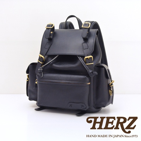 黑色皮革復古風旅行後背包，配有金色金屬扣和拉鍊，側面有兩個小口袋，正面有一個拉鍊口袋。