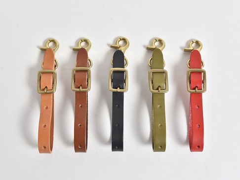 五個職人手作皮革可調式吊掛帶，從左至右分別為淺棕色、棕色、黑色、橄欖綠色和紅色，皆配有黃銅色鉤扣和方形調節環。