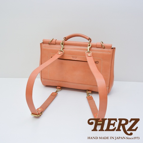 日本HERZ手工皮革屋瓦風側背包 CW-147，橘色，背面視角，展示雙肩帶和金色金屬扣。