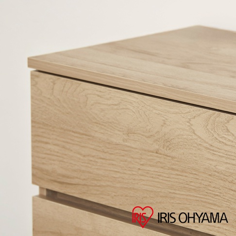 IRIS OHYAMA 木製收納櫃的局部特寫，展示了淺木紋理的櫃體表面與簡約的抽屜設計，採用無把手凹槽式開關，整體風格呈現出溫潤自然的日式居家質感。