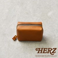 一個棕色皮革製成的箱型收納包，上面有拉鍊和一個小提把。